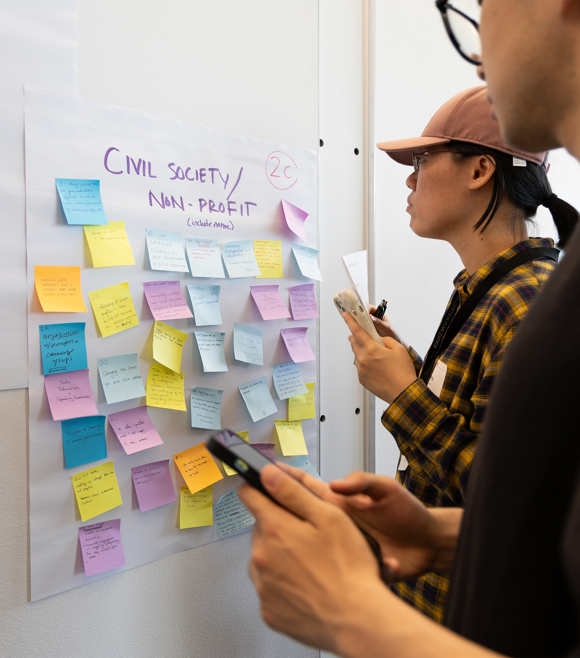 Two people put sticky notes on a wall.