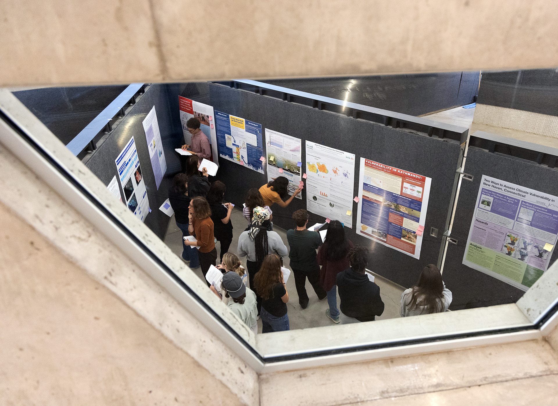 A group of people look at posters mounted on the walls.