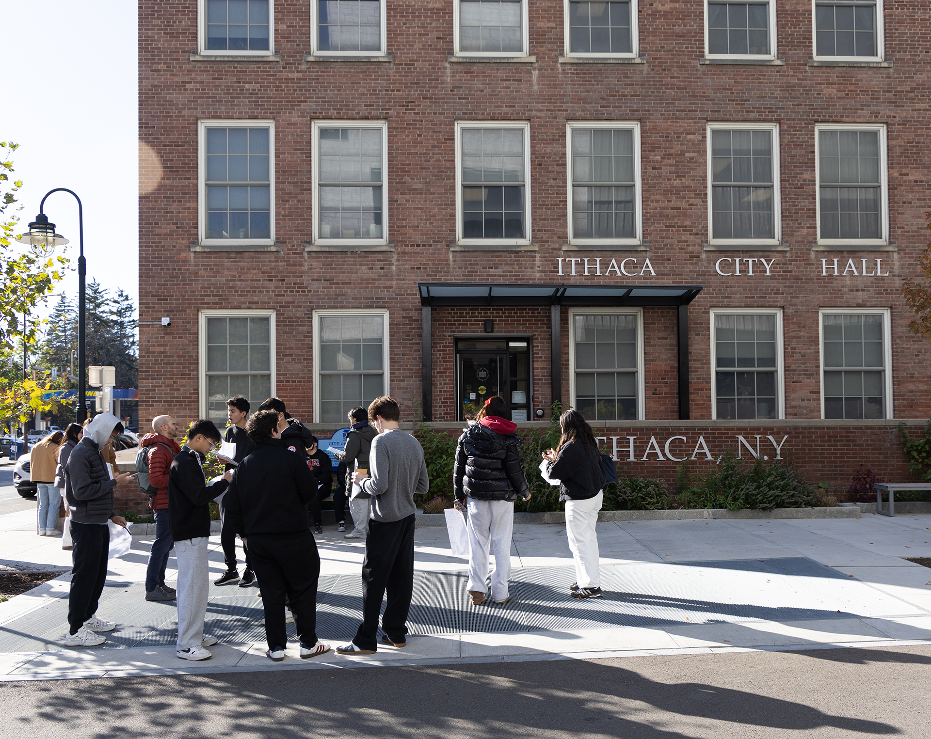 Exterior of a brick building with people gathered in front on the sidewalk.