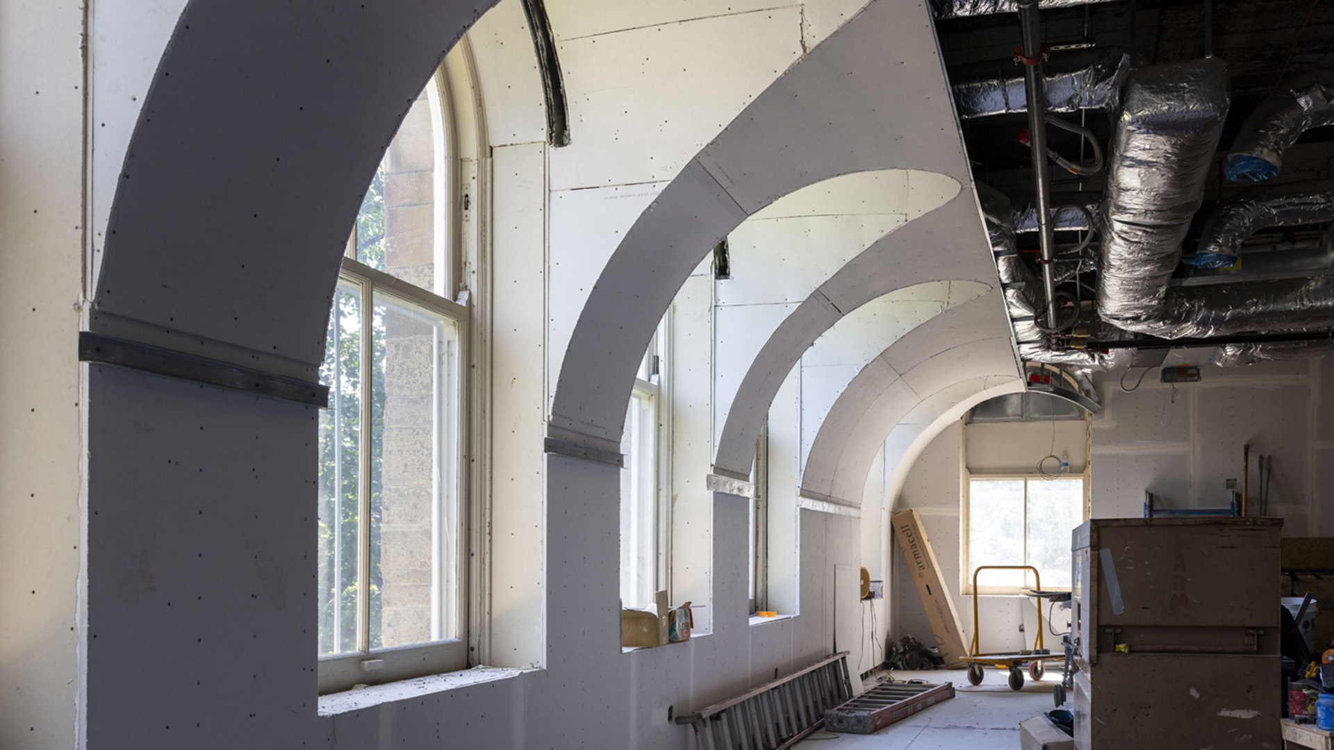 Interior of a building with a window lined wall that features curved arches extending into the main area of the building.