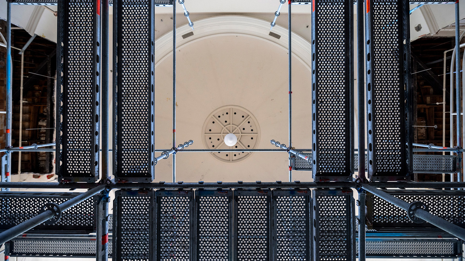 View through metal scaffolding upward toward a dome.
