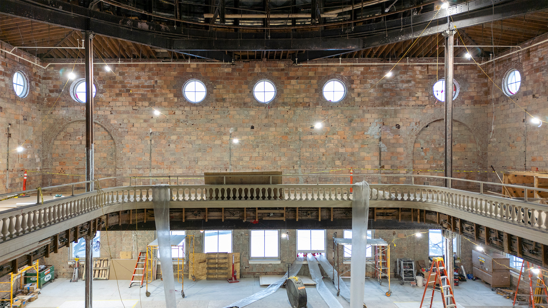 Interior of a brick walled building with small circle windows and balcony bannister.