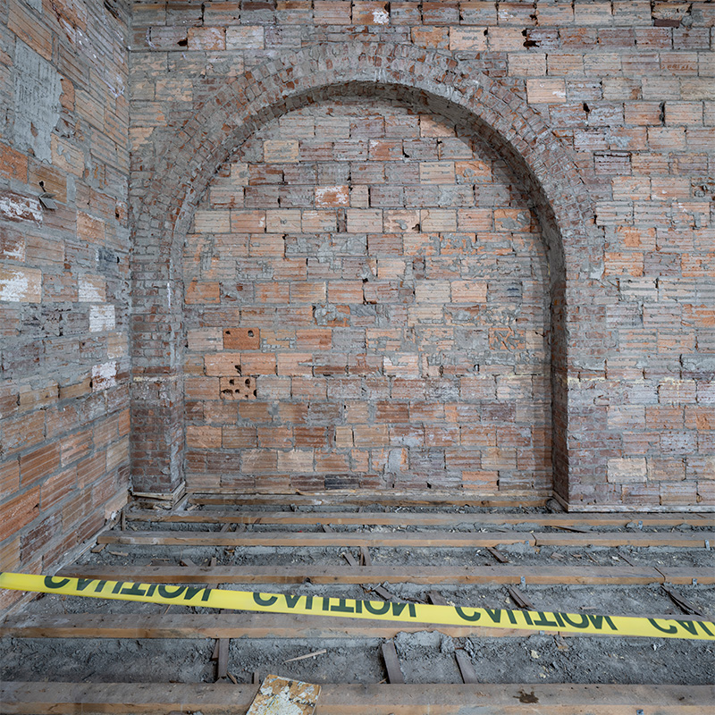 Brick wall with an archway hinting at a former window location.