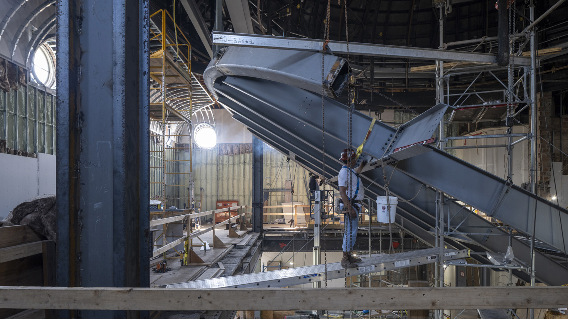 Cantilevered auditorium framing with construction workers inspecting the framing.