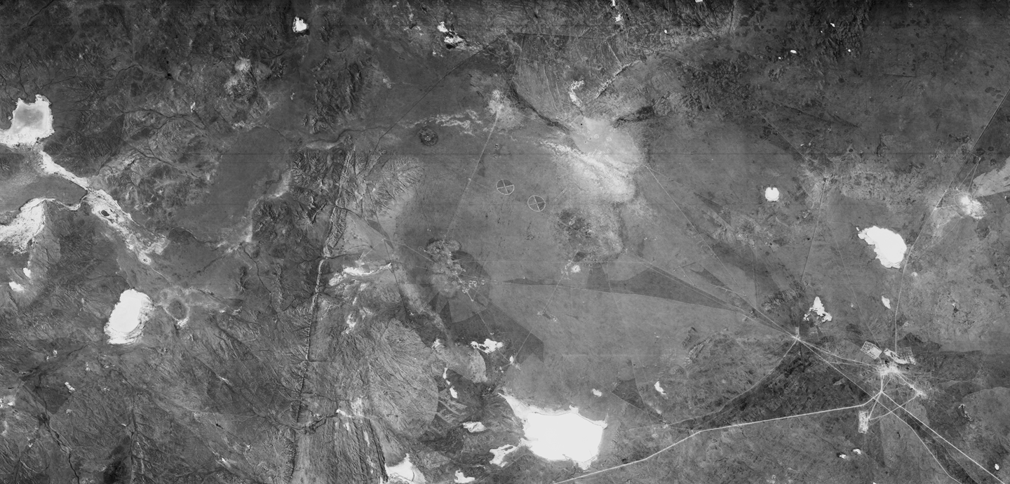 Aerial photograph of a landscape with roads and mountains in grayscale.