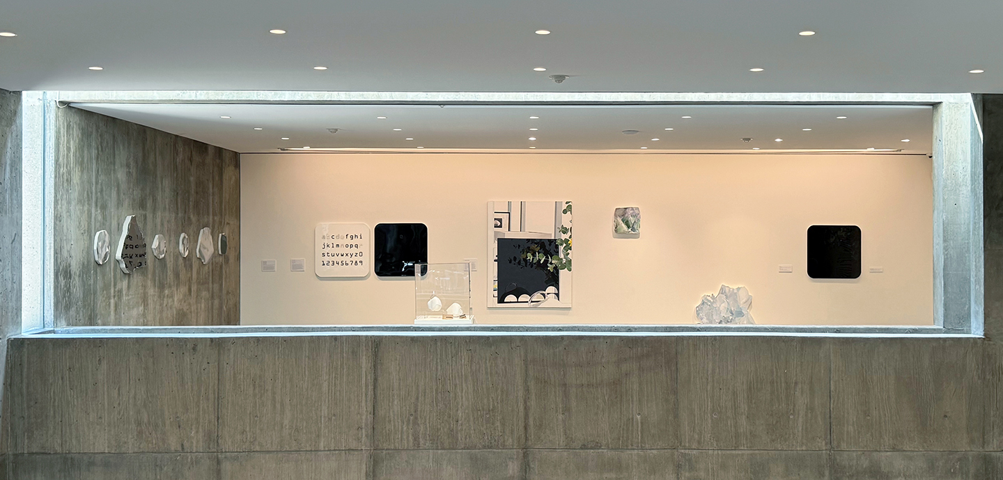 A concrete wall with a large glass window that leads to an art gallery with various stone sculptures and paintings.