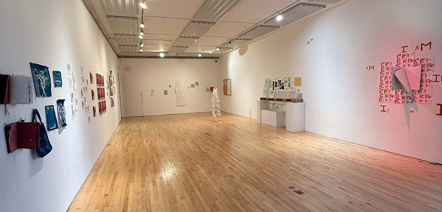An installation view of an art gallery: mounted on the right wall is a book with red text