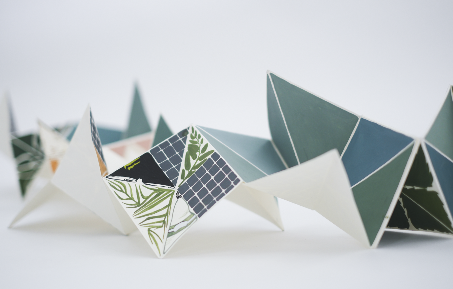 A long sheet of paper is folded into triangles that are colored with shades of green and blue.