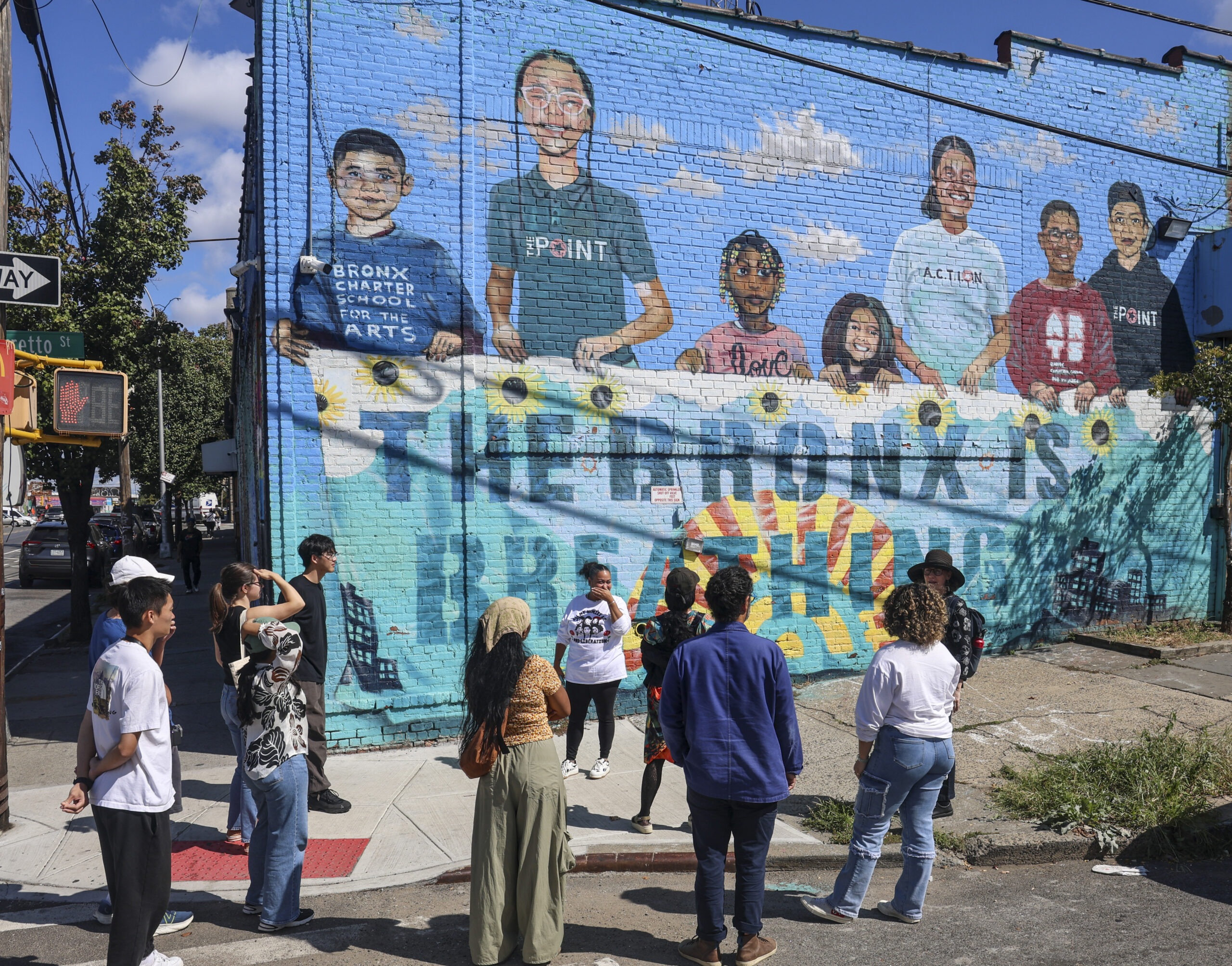 Students standing on a street corner viewing a mural