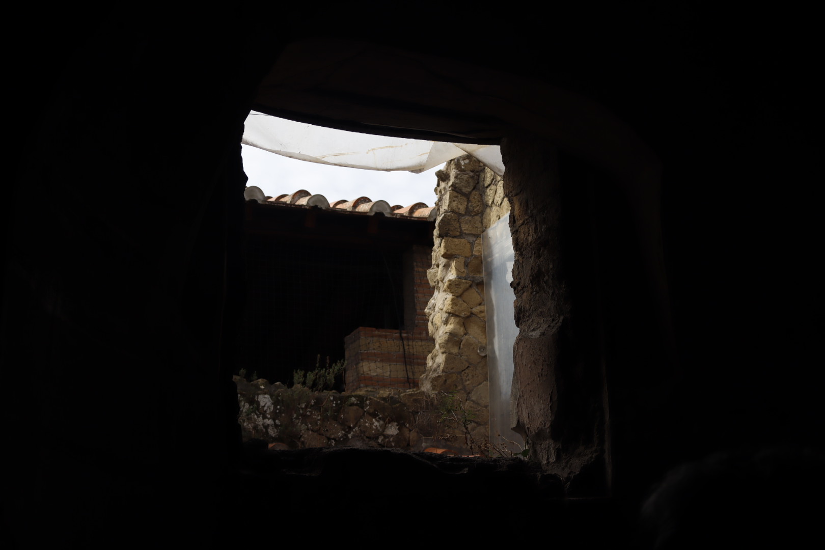 a room in shadow with bricks and tarp