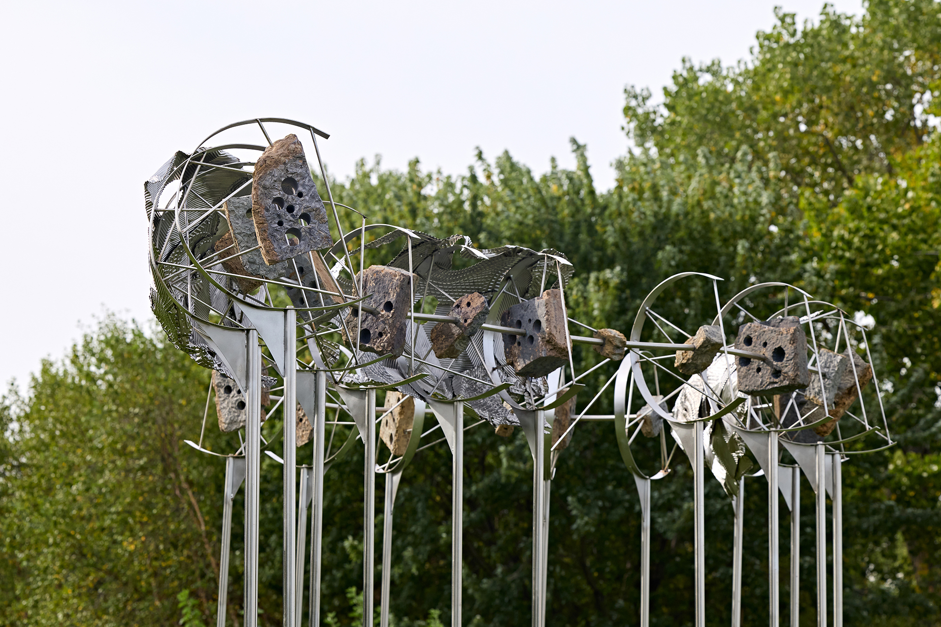 A large metal sculpture with trees in the background.