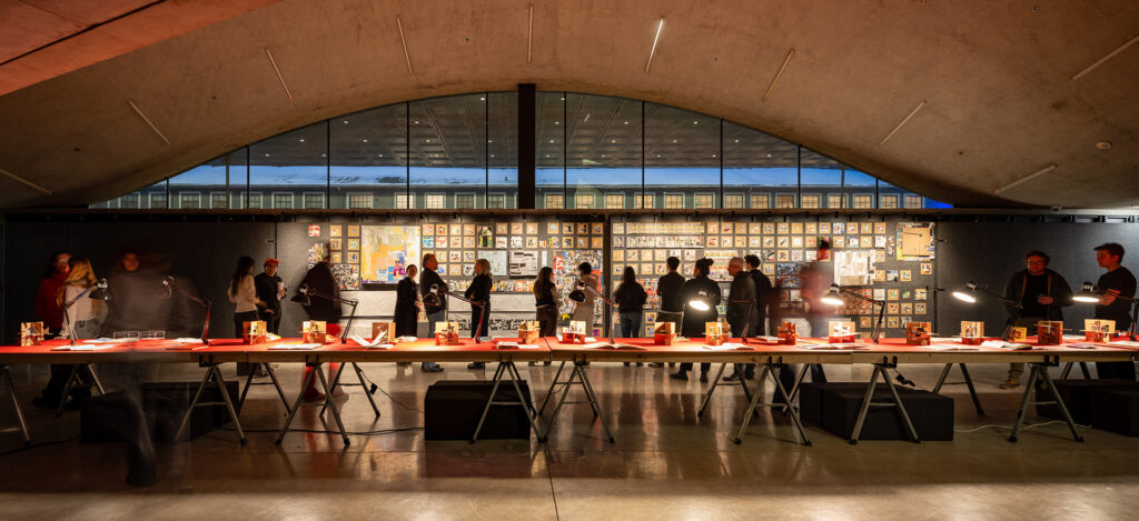 People examine a brightly lit exhibition of student models.
