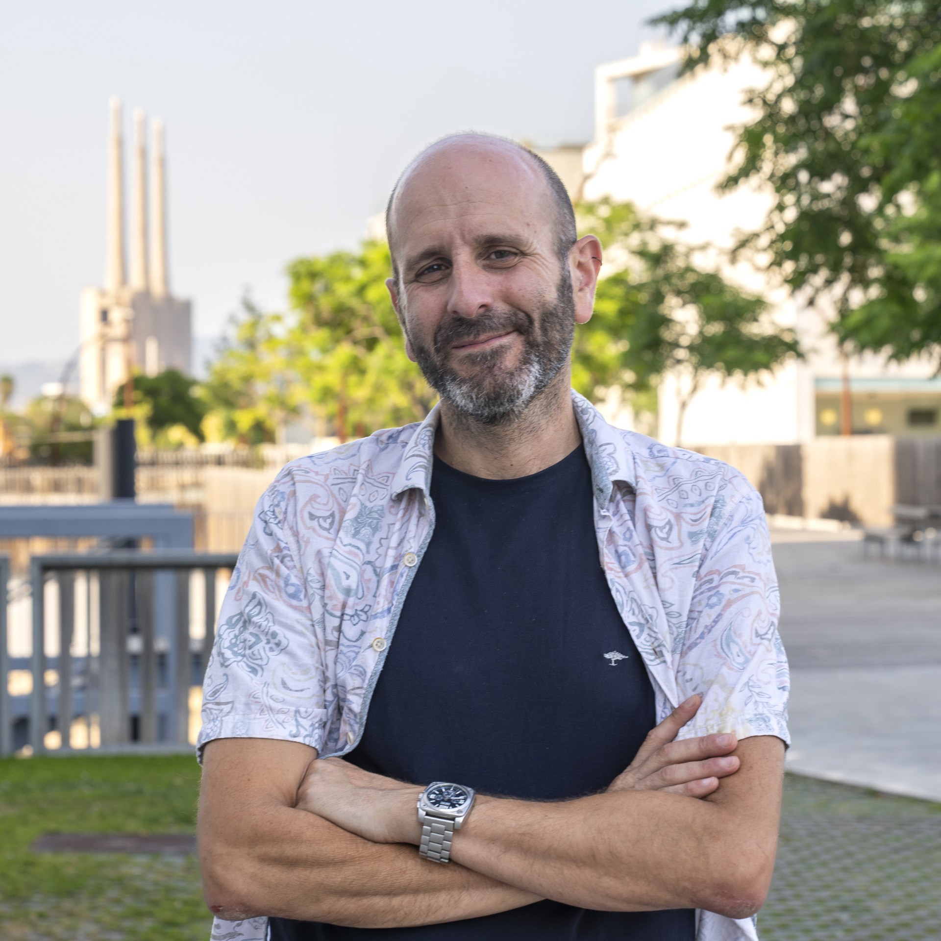 Headshot of architect Adolf Sotoca outdoors with a sunny blurred landscape in the background.