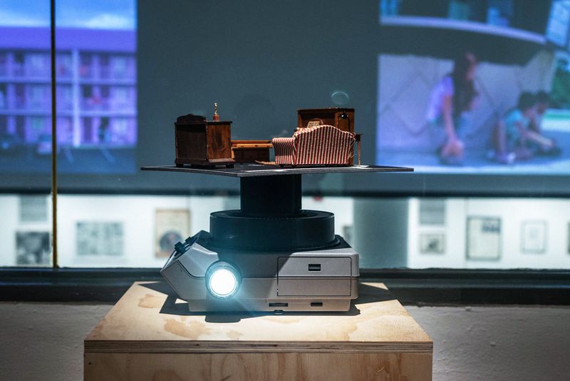 a projector sitting on a wooden pedestal with an architectural model on top