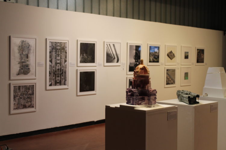 a gallery wall with framed images and pedestals with objects on them