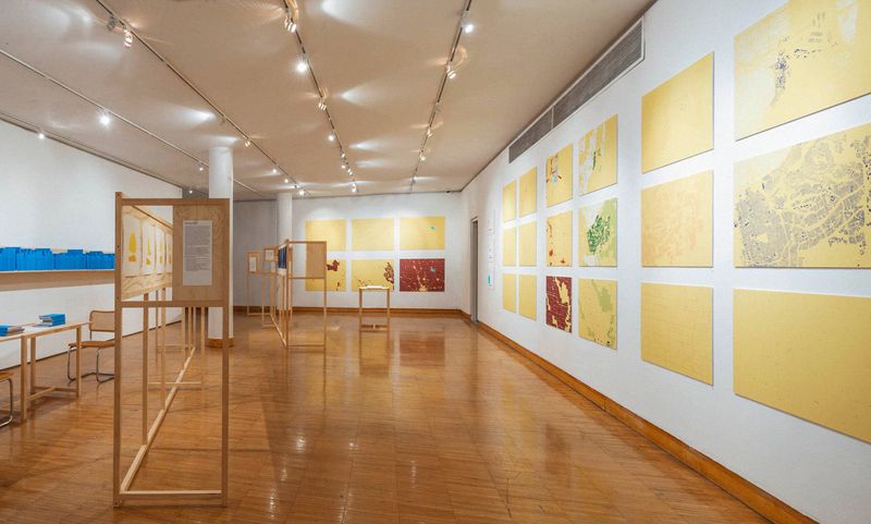 a gallery with white walls and shiny wooden floors with artwork on the walls