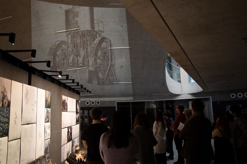people observing pinned artworks on a wall and a projected image