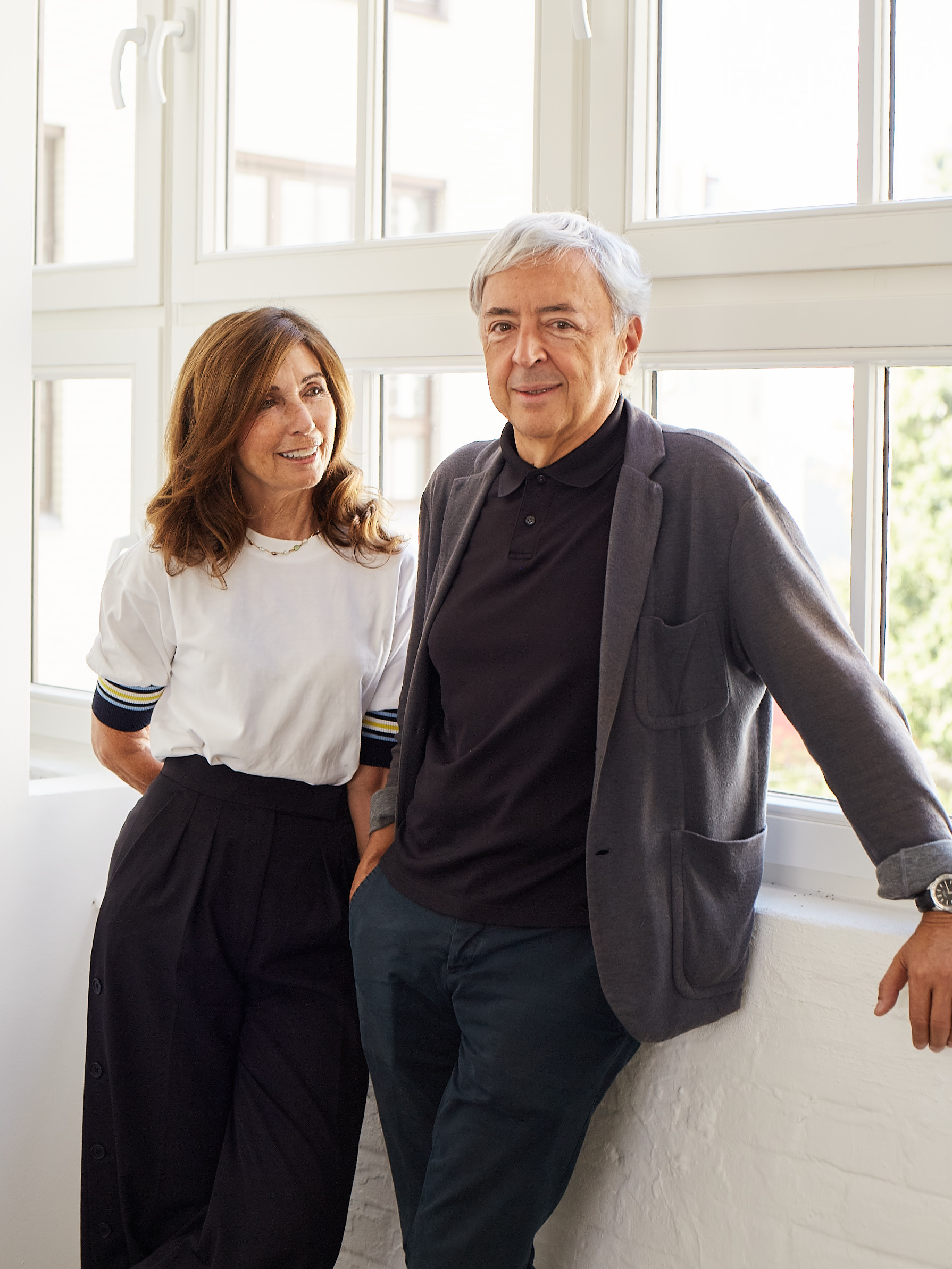 Color portrait of architects Fuensanta Nieto and Enrique Sobejano posed in front of a window