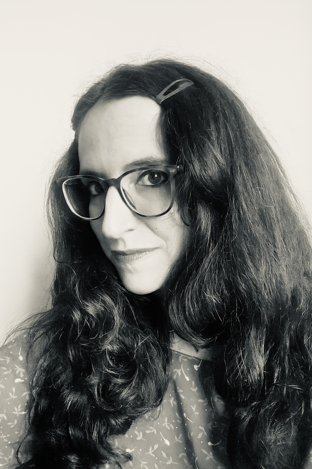 A woman with long dark hair and glasses.