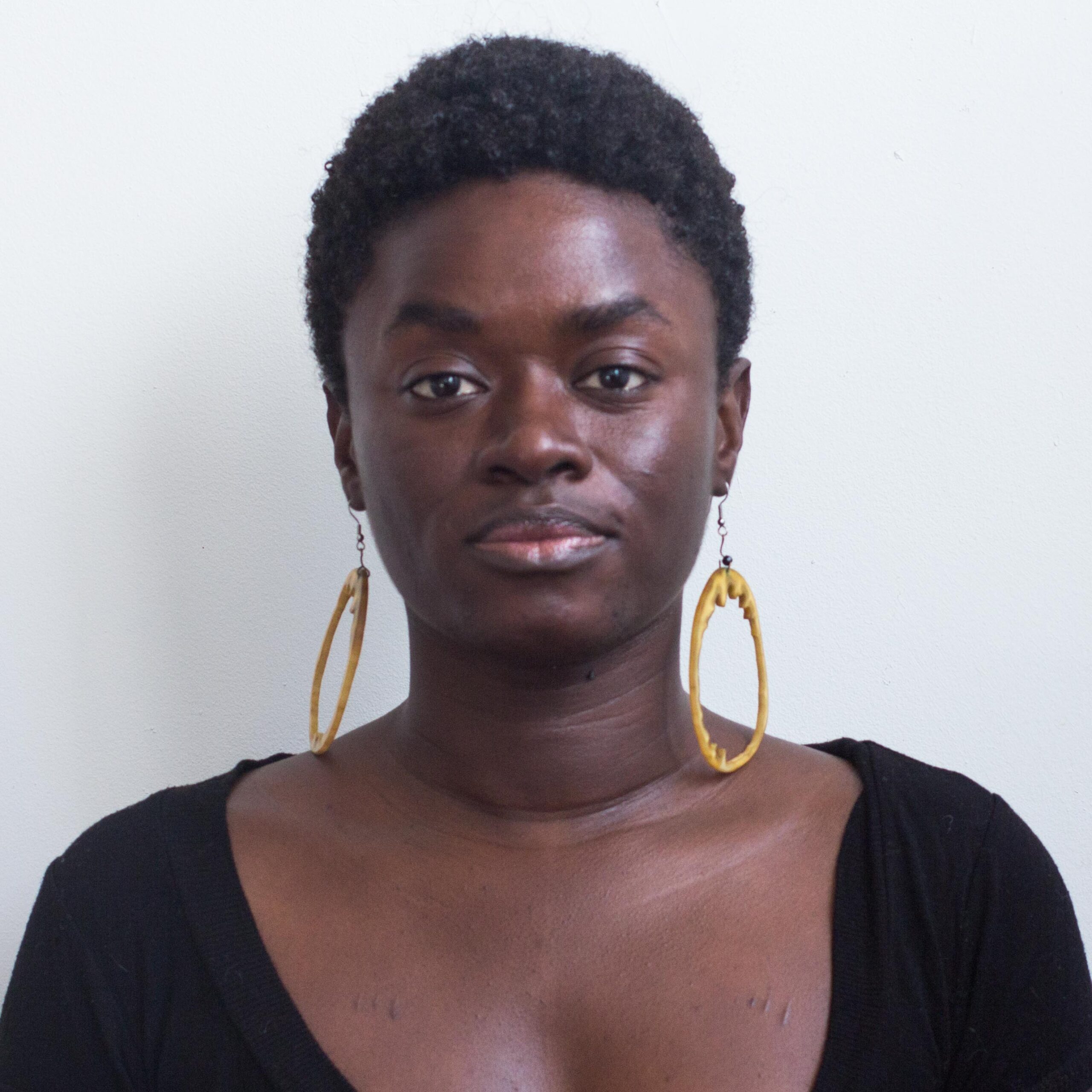 A woman with short Afro-textured hair and large gold hoop earrings