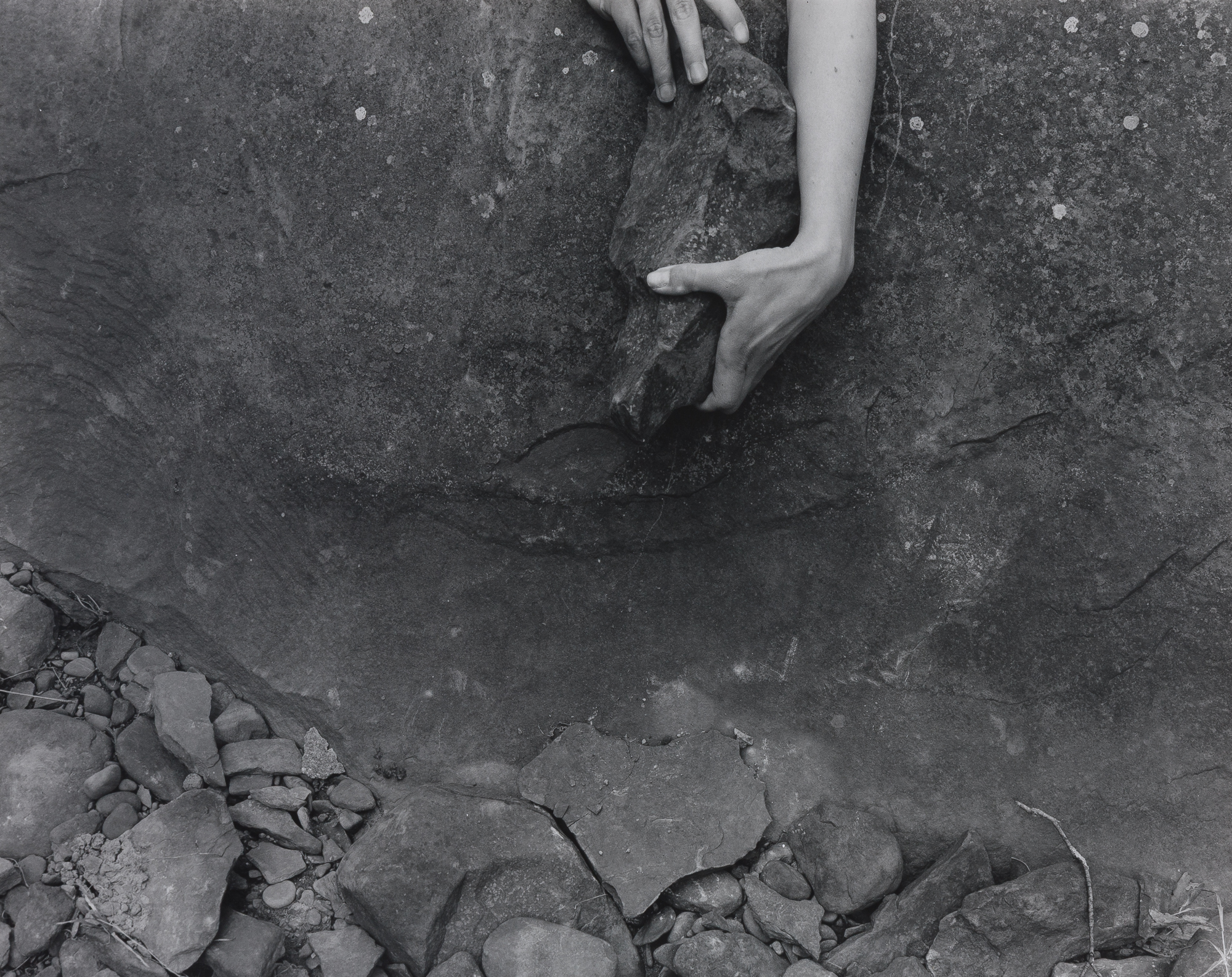 Two hands holding a large rock