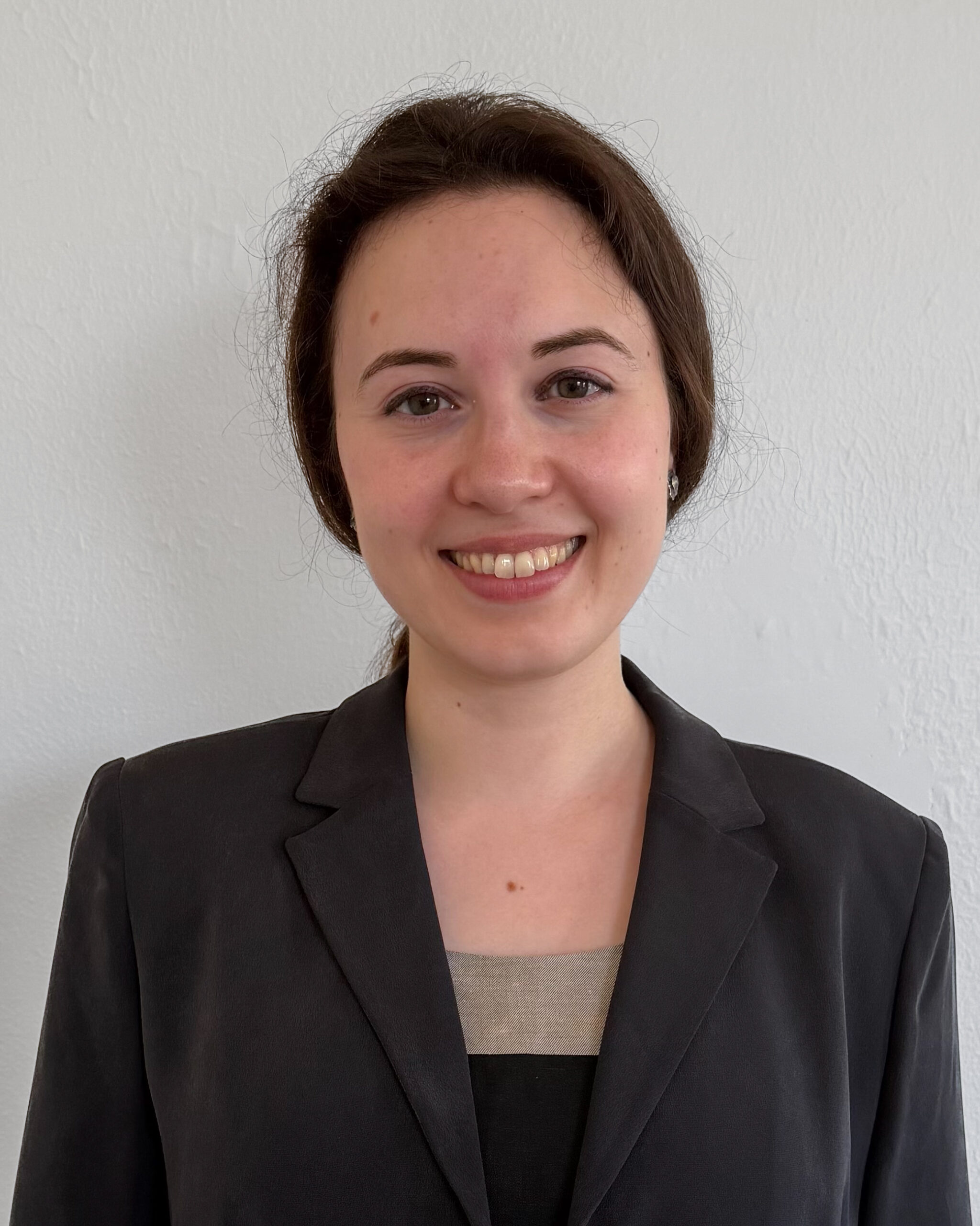 headshot of a fair-skinned woman with brown hair pulled back in a ponytail, wearing a dark gray blazer