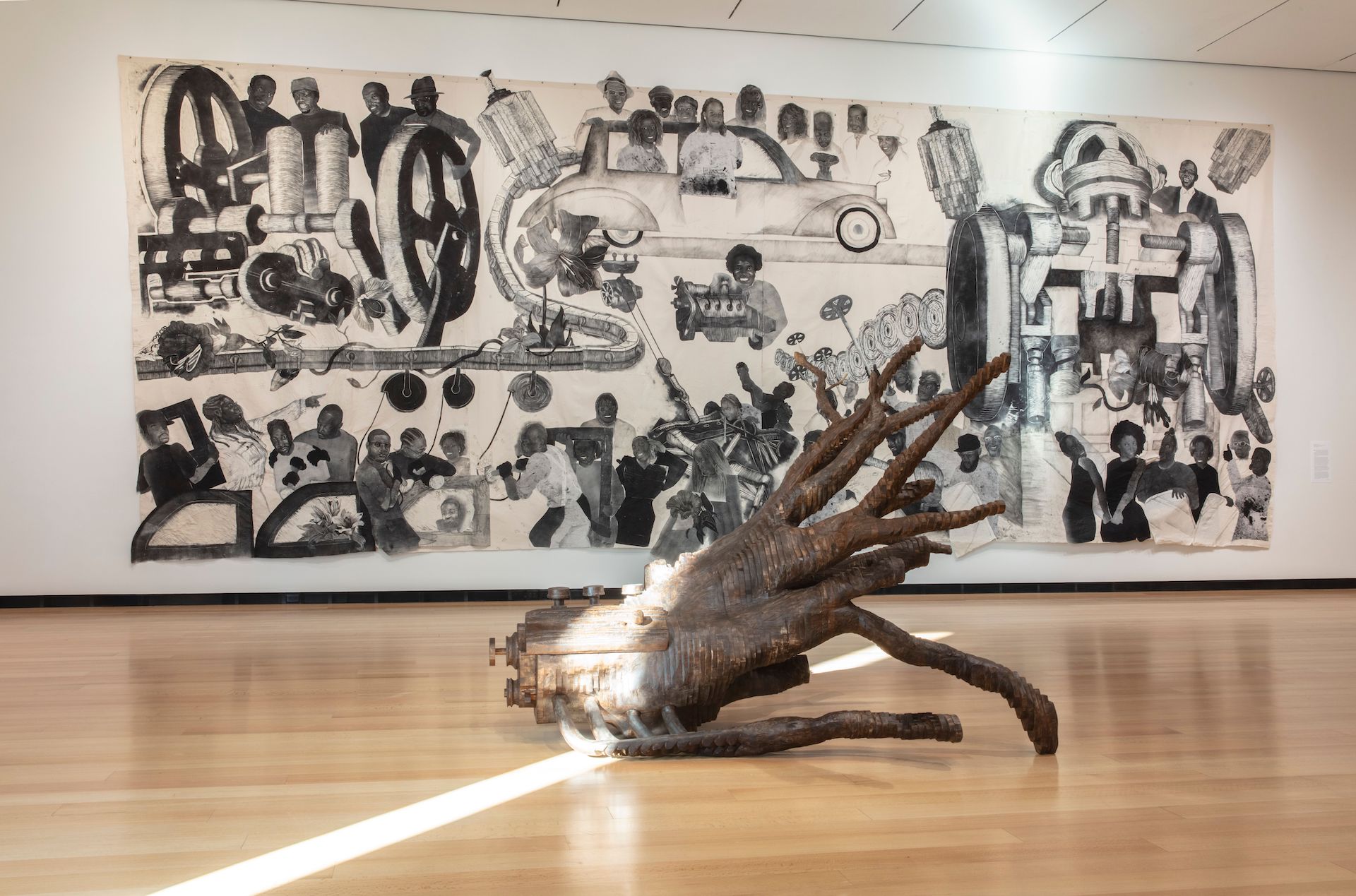 An art gallery with a tentacle-like sculpture in the middle and a mural on the back wall.