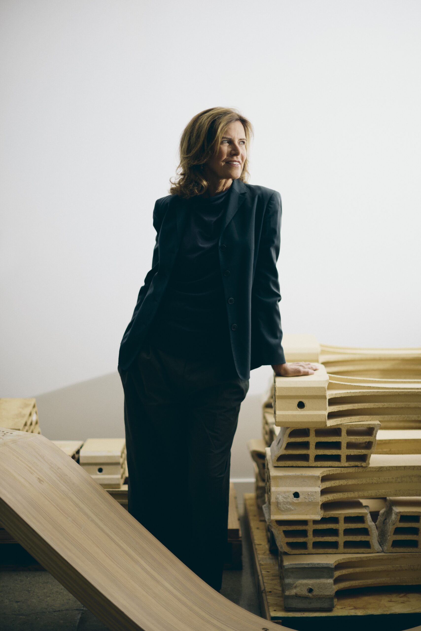 woman in a dark suit leaning on an wooden architectural model