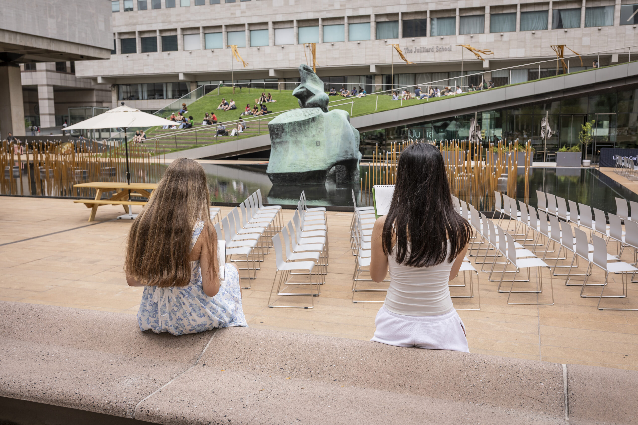 Two people sitting and sketching a sculpture