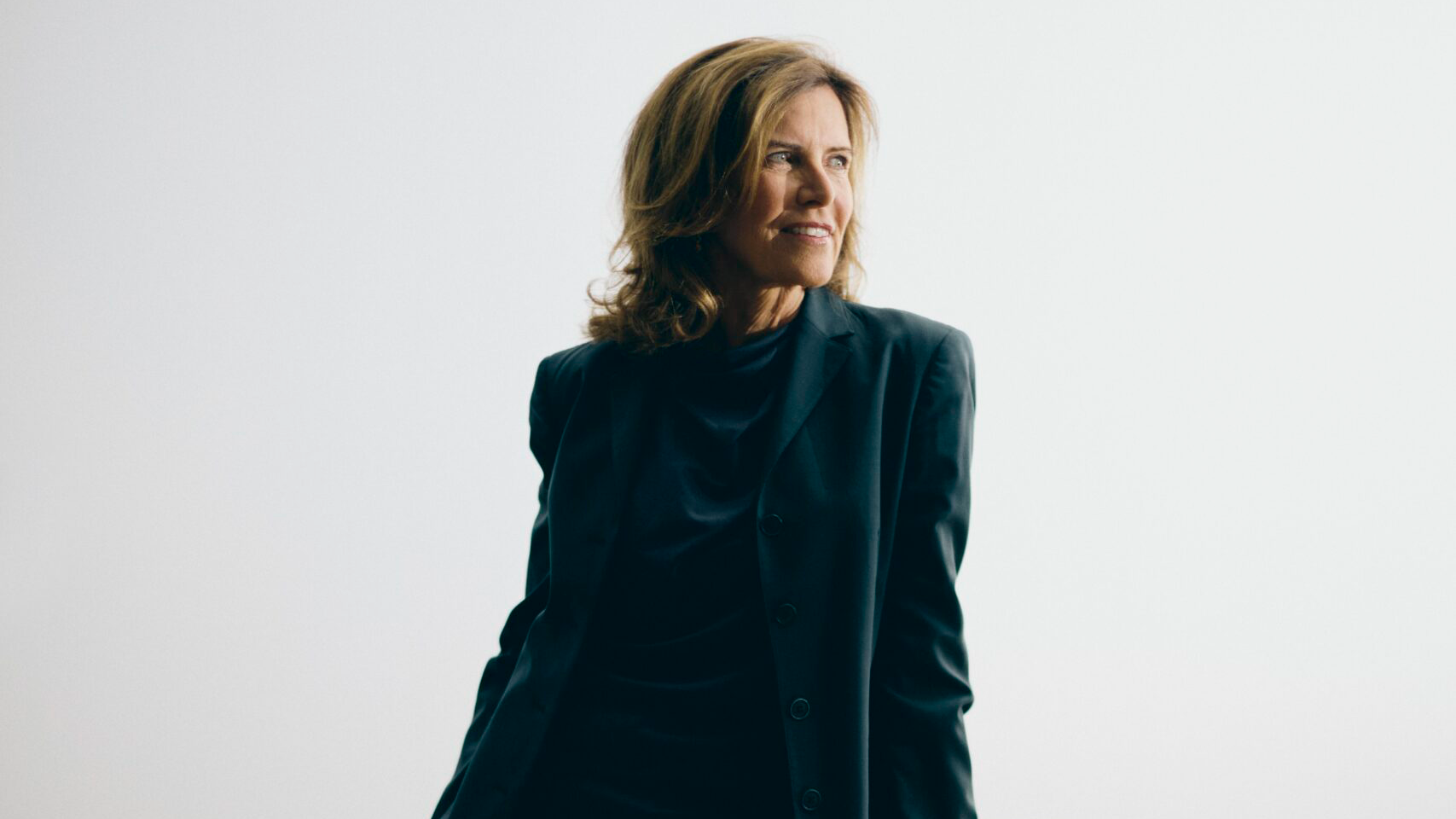 woman in a dark suit leaning on an wooden architectural model